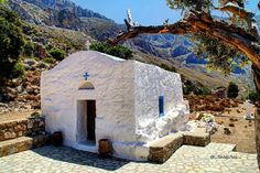 an old white church in the mountains with a cross on it's door and steps leading up to it