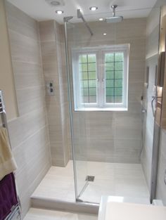 a bathroom with a walk in shower next to a white sink and toilet under a window