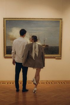 a man and woman standing in front of a painting on display at an art museum