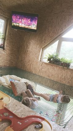 two children laying on the ground in front of a tv screen and some sand toys