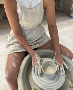 a woman sitting on top of a pottery wheel