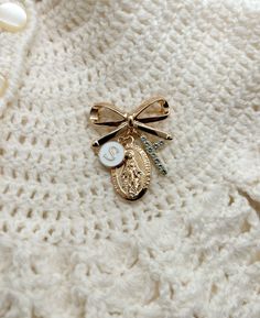 a close up of a sweater with a bow tie and charms on the front pocket