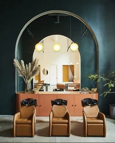 three brown chairs sitting in front of a mirror