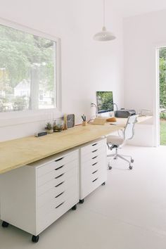 a desk with a computer monitor, keyboard and mouse on it in front of a window