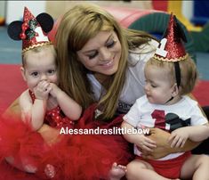 a woman and two children wearing minnie mouse hats on their heads, sitting in front of a red carpet