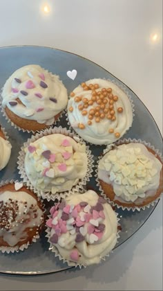 cupcakes with white frosting and sprinkles are arranged on a plate