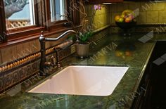 a kitchen sink sitting under a window next to a counter top with a potted plant