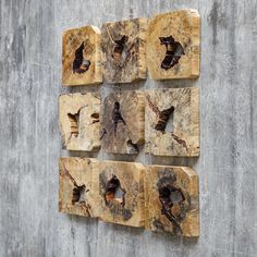 four pieces of wood with holes in them on a concrete wall, one is missing