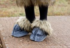 the legs and feet of a person wearing furry shoes with blue jeans, black socks, and fur