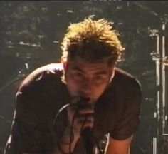 a man holding a microphone up to his face while standing in front of a stage