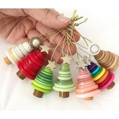 a hand holding a bunch of colorful wooden christmas tree ornament ornaments in different colors