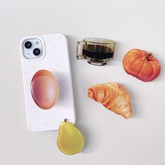 an iphone case with some food on it and a cup next to the phone holder