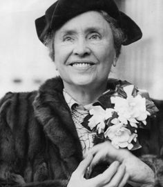 an old woman wearing a hat and fur coat holding a bouquet of flowers in her hands