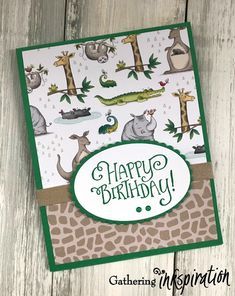 a happy birthday card with animals and giraffes on the front, sitting on a wooden surface