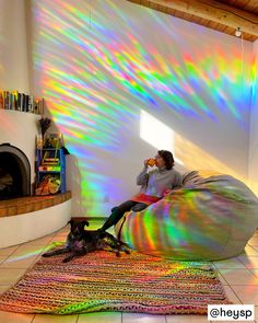 a woman sitting on a bean bag chair in front of a fire place and a cat