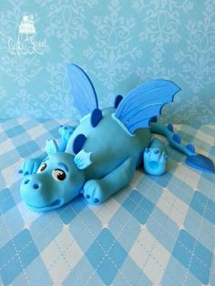 a blue dragon figurine laying on a checkered tablecloth