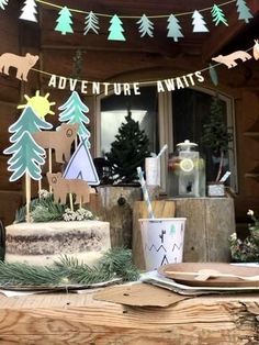 a table topped with a cake covered in frosting next to a forest themed sign