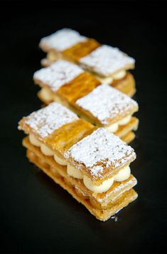 some desserts are stacked on top of each other with powdered sugar toppings