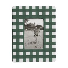 a green and white checkered photo frame with a boy running on the beach in front of a house