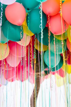 many colorful balloons are hanging from the ceiling