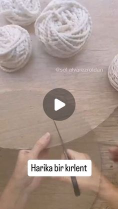 the video shows how to crochet with yarn and cotton balls on a wooden table