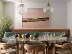 a dining room table with four chairs around it and a painting on the wall behind it