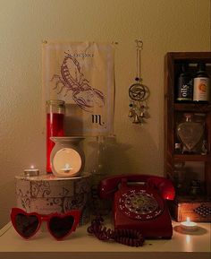 a red telephone sitting on top of a table next to a candle and other items