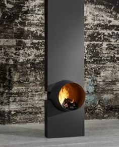 a black fire place sitting on top of a cement floor next to a brick wall