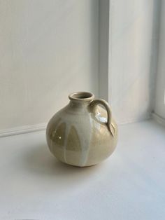 a white and gray vase sitting on top of a window sill next to a wall