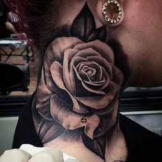 a woman's neck with a rose tattoo on it