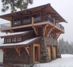 a large wooden building sitting on top of a snow covered slope next to a forest