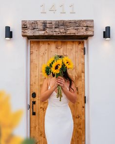 a woman in a white dress holding sunflowers