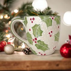 a green and white coffee cup sitting on top of a table next to christmas decorations