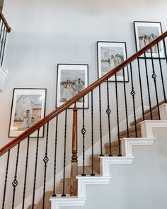 a staircase with pictures on the wall and framed photos on the bannister rail