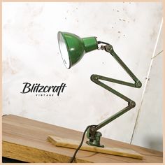 a green desk lamp sitting on top of a wooden table