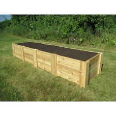 a wooden garden box filled with dirt in the grass