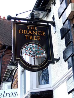 an orange tree sign hanging from the side of a building