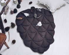 a table topped with lots of pine cones next to a wooden chair and white sheets