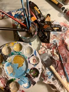 an artist's palette with paint, brushes and other art supplies on the table