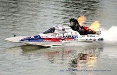 a speed boat speeding through the water with flames coming out of it's engine