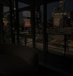 a couch sitting in front of a window with the city lights lit up behind it