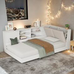 a white bed sitting on top of a wooden floor next to a wall covered in lights