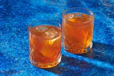 two glasses filled with liquid sitting on top of a blue counter