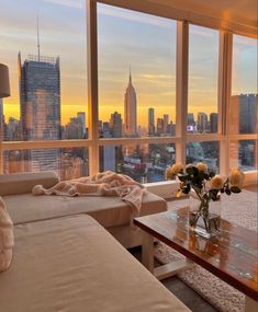 a living room filled with furniture and large windows overlooking the cityscape at sunset