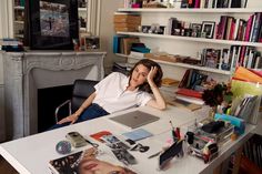 a woman sitting at a desk in front of a book shelf with books on it