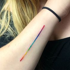 a woman's arm with a rainbow colored tattoo on the left side of her arm