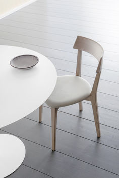 a white table with two chairs and a plate on top of it in front of a wall