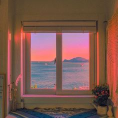 an open window overlooking the ocean at sunset or sunrise with pink and purple hues