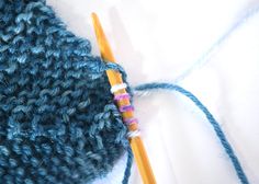 a blue knitted hat with two knitting needles next to it