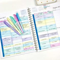 an open planner with pens on top of it next to a cell phone and other items